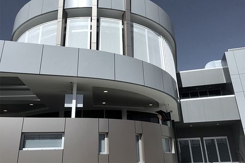 A curved band of grey panels over a building entry, with bronze panels below.